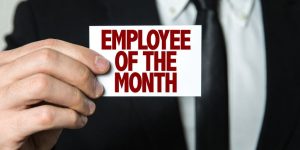 A man holding a card that reads "EMPLOYEE OF THE MONTH"