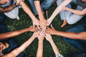 People huddled in a circle with hands in the middle