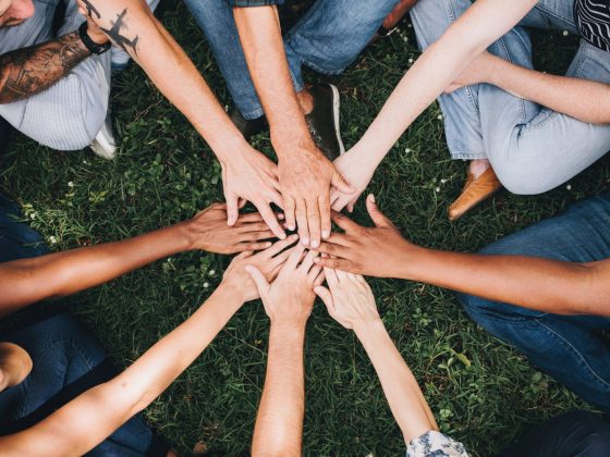 People huddled in a circle with hands in the middle