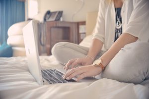 A woman in bed on a laptop researching employee retention