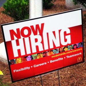 A sign that reads "NOW HIRING"