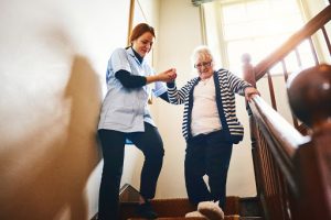 Someone providing home healthcare to an elderly woman on the stairs